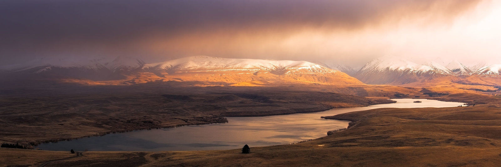 Stormy sunrise illuminates Lake Tekapo and surrounding mountains, New Zealand